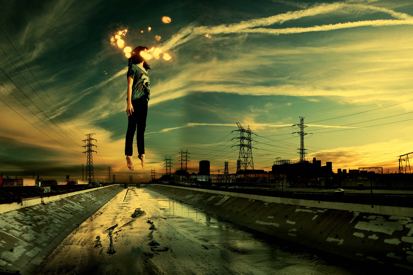 This mesmerizing digital collage presents a woman suspended in mid-air above the LA river skyline at sunset. Bathed in tones of green and yellow, the composition is further enhanced by streaks of clouds in the sky and sparks of light that add an ethereal touch to the scene.