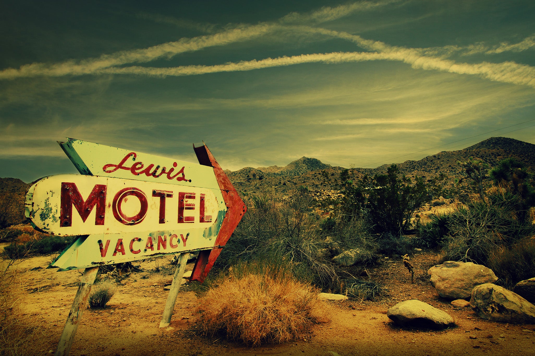 "Lewis Motel" by Shannon Black is a fine art photograph that showcases a vintage hotel sign standing in the the Joshua Tree desert, creating a striking juxtaposition between the remnants of the past and the timeless beauty of nature.