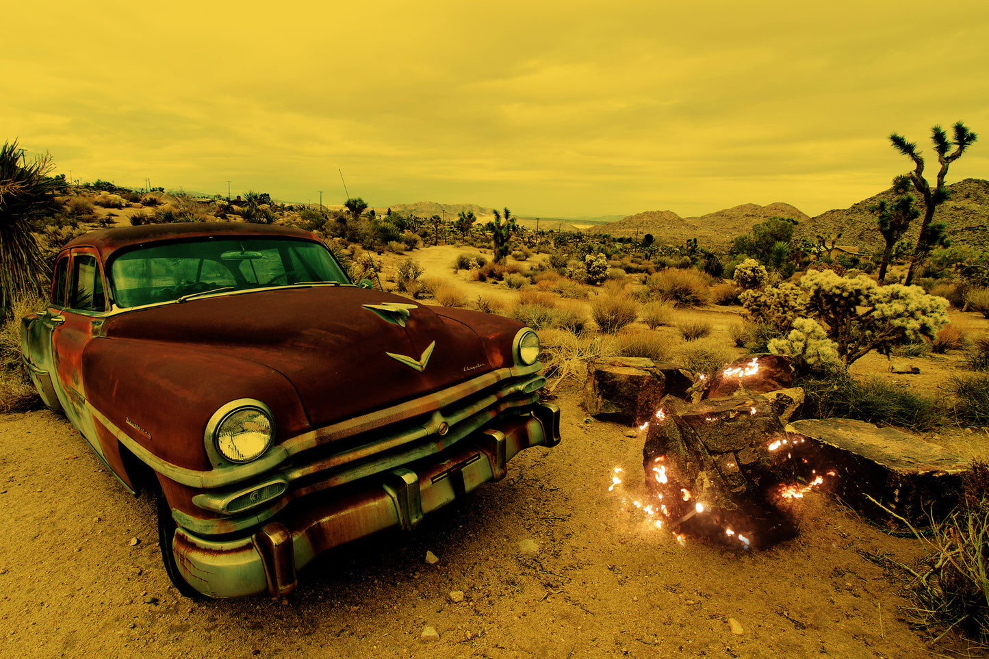 "Light Theory #5" by Shannon Black is a fine art photograph that transports viewers into a realm where light, texture, and history converge in the mesmerizing landscape of the Joshua Tree desert. The image presents a juxtaposition of elements, with a rusted vintage Chrysler in the foreground and sparks overlaying a rock, creating an ethereal atmosphere that sparks contemplation and imagination.